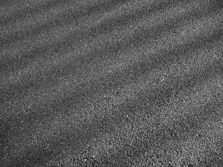 wet asphalt road with dark shadow of fence and light of morningの写真素材