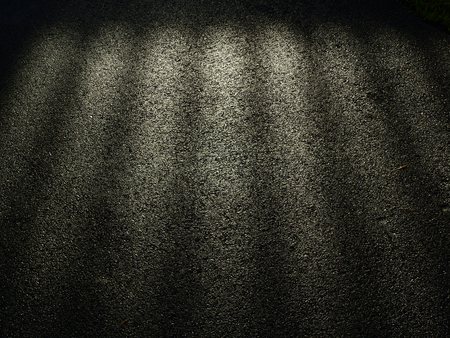 wet asphalt road with dark shadow of door and light of morningの写真素材