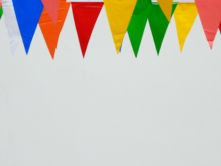 colorful flags festival hanging with white wall backgroundの写真素材