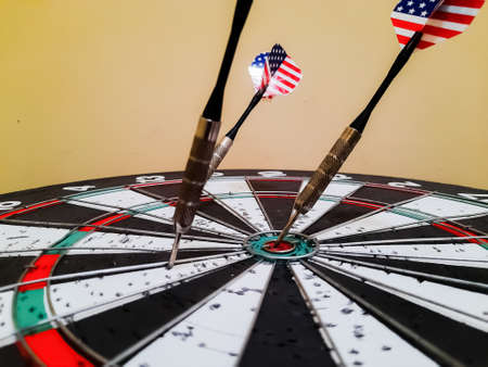 Photo of three darts that hit the dart board and one hitting the bulls eye