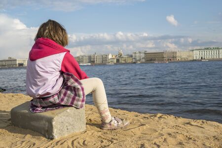 Girl sitting on the beach and look at the panorama of St. Petersburgのeditorial素材