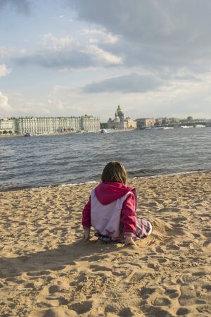 Girl sitting on the beach and look at the panorama of St. Petersburgのeditorial素材