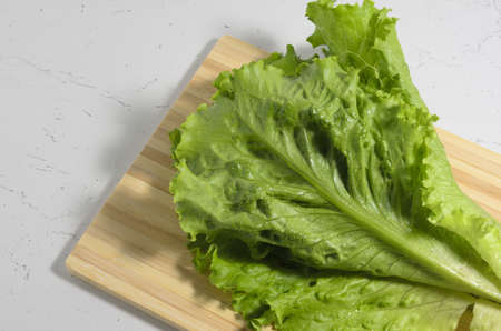 Green lettuce leaf on cutting board and texture table top on the background. Selective focus.の写真素材