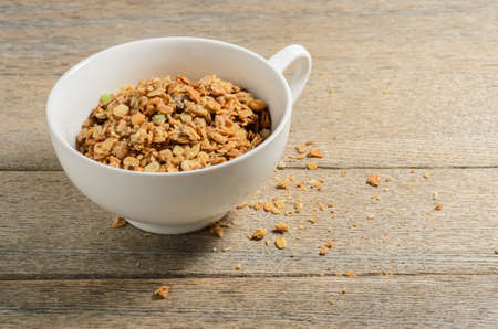 Muesli in a white bowl against the background of old village ash planks. Selective focus.の写真素材