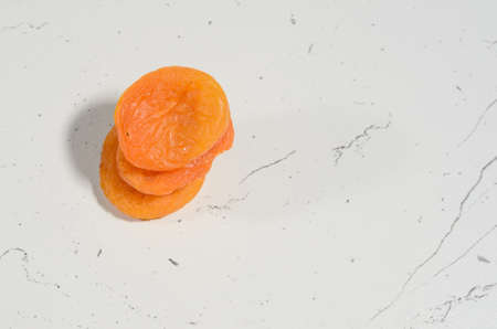 A few berries of bright dried apricots on a background of textural black and white surface.の写真素材