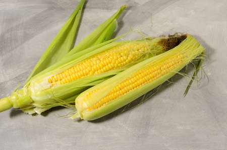 A ripe corn cob with leaves and yellow grains. Texture surface as a background.の写真素材