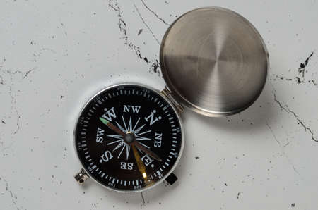 An old compass with an iron lid with scratches on the textured surface of the table. Selective focus.の写真素材