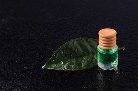 Lemon flavor of emerald color in a glass bottle with a wooden stopper on a green leaf with water droplets.の写真素材