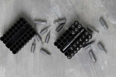 Screwdriver bits for various standards in a convenient package on a gray concrete background.
