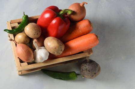Vegetables in a wooden box. Set of vegetables, potatoes, onions, garlic, pepper, beets on a textured background.の写真素材