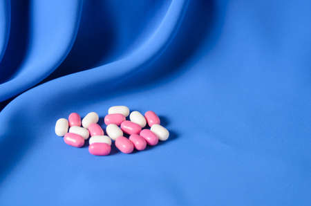 White and pink pills on a blue silk wavy background. Tablets for refreshing the oral cavityの写真素材