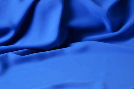 The blurred, defocus background is made of a delicate blue chiffon fabric with folds in the form of...