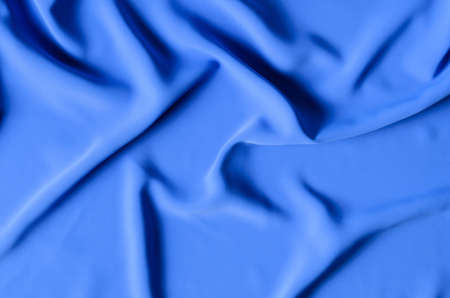 The background is made of a delicate blue chiffon fabric with folds in the form of waves. Top view....