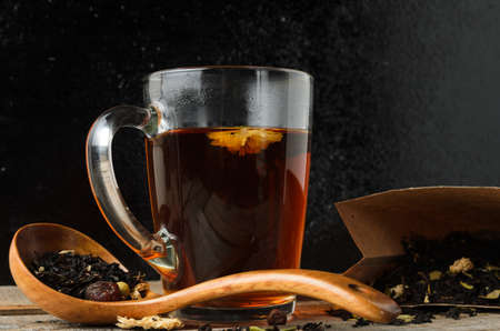 A glass mug of fragrant brewed flower tea on a wooden table, with a wooden spoon, in a rustic style....
