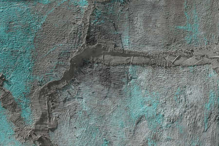The texture of a gray with turquoise spots of a cracked cement wall with a smeared crack....