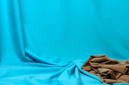 Crumpled fabric in pale blue and beige with elegant pleats for the background. Selective focus.の写真素材