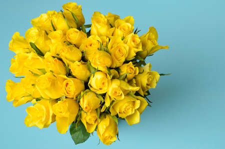A bouquet of many delicate, yellow roses on a textured, blue, silk background. Selective focus.の写真素材