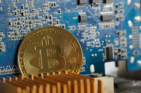 Golden bitcoin on the background of an electronic computer board. Selective focus.の写真素材