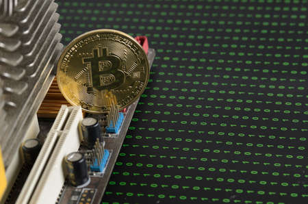 Gold bitcoin in the radiator of the graphics card, binary code on a blurry black background. Selective focus.の写真素材
