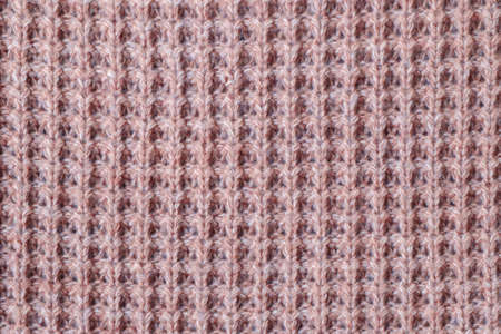 Texture of knitted woolen fabric of light red color close-up.の写真素材