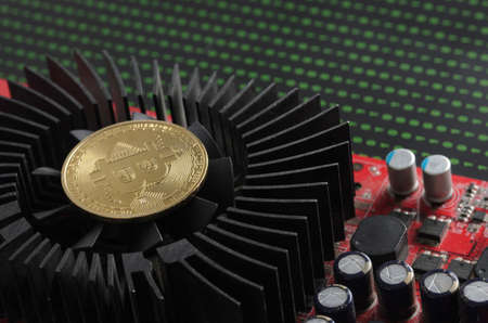 A bitcoin gold coin on a cooling fan against the background of binary codeの写真素材