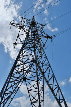 A high-voltage metal pylon against a blue cloudy sky.の写真素材