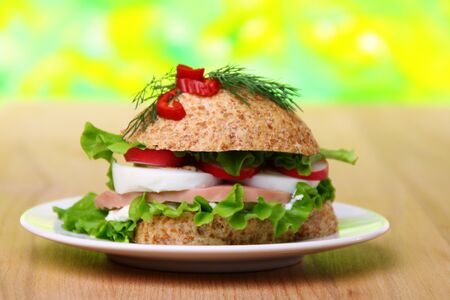 Plate with a sandwich of corn bread with lettuce, ham on wooden table.の写真素材
