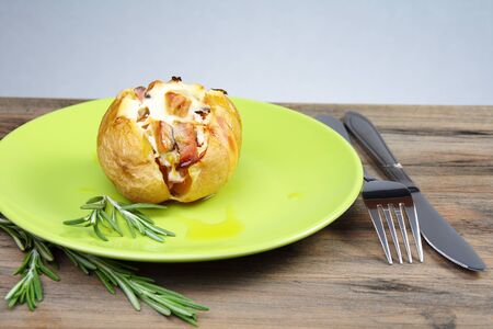 Baked potatoes with rosemary on a green plate.の写真素材