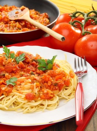 Spaghetti with sauce and ripe tomatoes on a wooden table.の写真素材