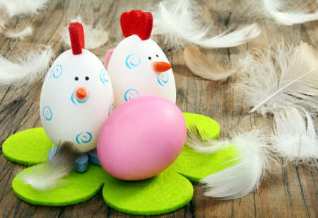 Funny Easter eggs and feathers on a wooden board.の写真素材