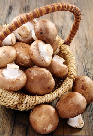 Fresh brown mushrooms in basket on a wooden table.の写真素材