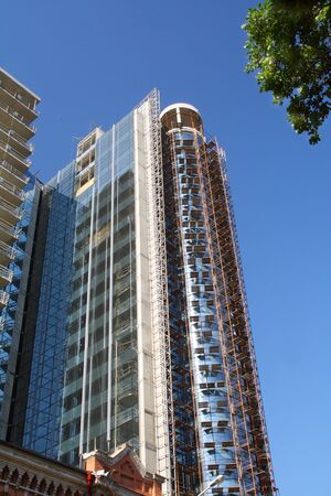 Modern building under construction in glass and concrete against the blue sky の写真素材