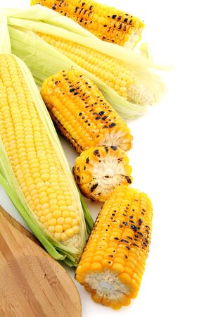 Cleaning freshly roasted ears of corn on cob with green leaves on a white background.   の写真素材