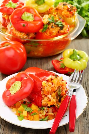 Sweet peppers stuffed with vegetables and ripe tomatoes on a wooden table の写真素材
