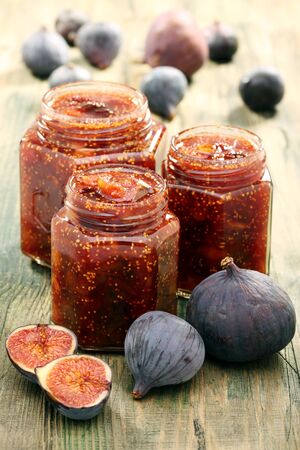 Figs and jam in glass jars on a wooden table の写真素材