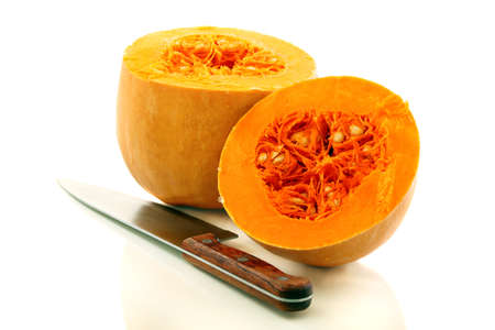 Two halves of a ripe pumpkin and a table knife on a white background の写真素材