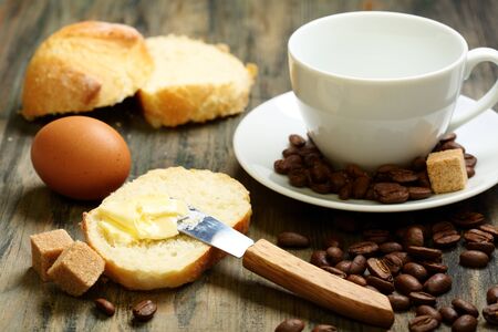 Coffee beans, eggs, bread and butter on a wooden table 