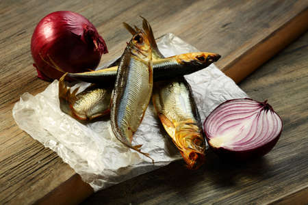 Smoked sprat and red onion on a wooden board の写真素材