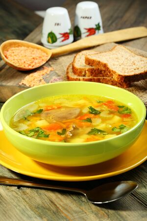 Chicken soup with red lentils in green cup on a wooden table  の写真素材