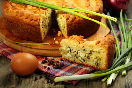 Pie stuffed with eggs and onions on a wooden table の写真素材