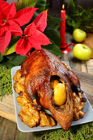 Duck with apples, poinsettia flower and candle on a wooden table の写真素材