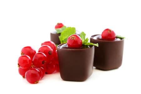 Handmade chocolates decorated with red currants on a white background の写真素材