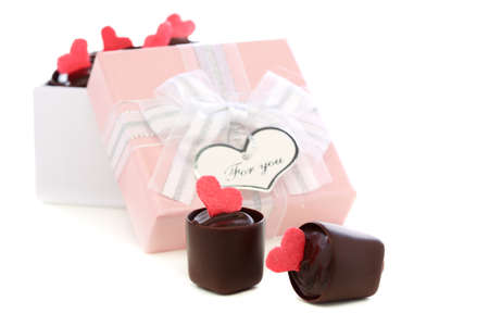 Handmade chocolates and pink box with a bow on a white background の写真素材