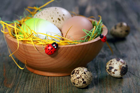 Colored eggs in a bowl on a wooden table 
