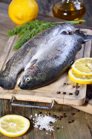 Trout on cutting board, lemon and a bottle of oil  の写真素材