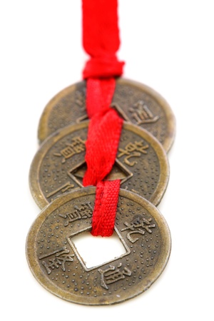 Three Chinese coins tied with red ribbon on a white background の写真素材