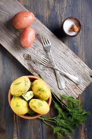 Boiled potatoes, dill and fork on old wooden table.の写真素材