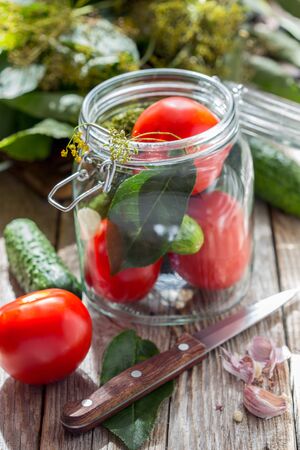 Glass jar with vegetables and spices on a country table.の写真素材