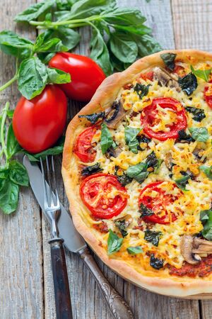Pizza with mushrooms, cheese and tomatoes on a wooden table.の写真素材