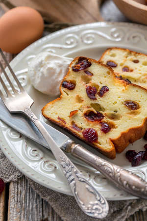 Cottage cheese casserole with sour cream on the porcelain plate.